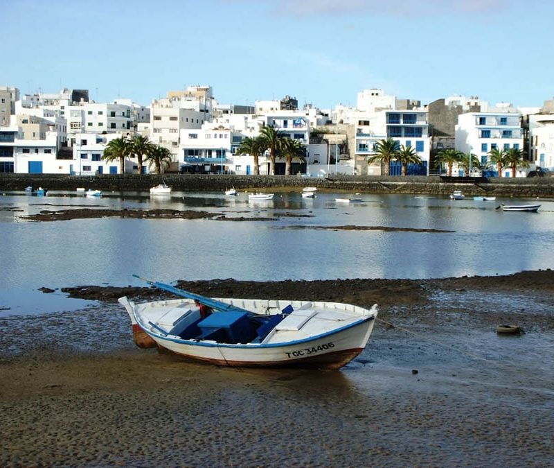 White boat on volcanic beach looking over houses in the distance